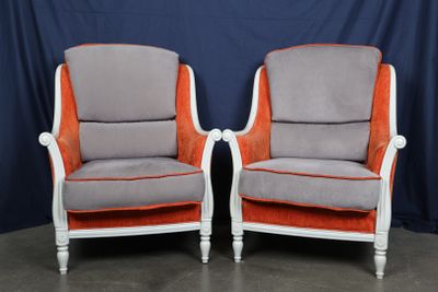 une paire de fauteuils rembourrés orange et gris sur fond bleu