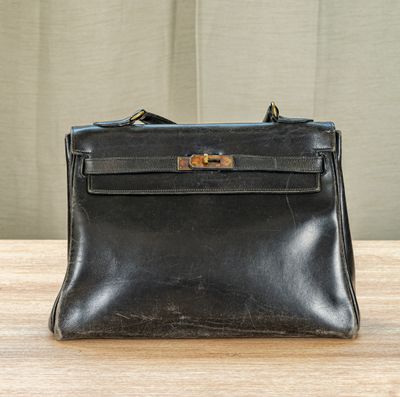 an old black purse sitting on top of a wooden table
