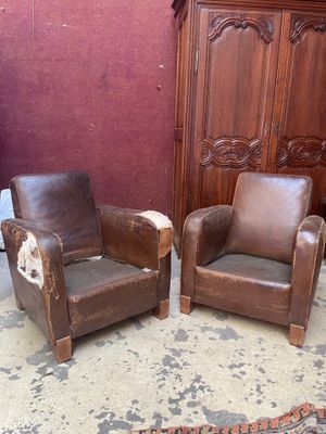 deux fauteuils en cuir marron placés l'un à côté de l'autre dans une pièce