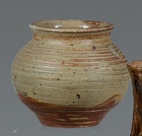 un vase marron posé sur une table à côté d'une souche d'arbre