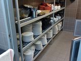 many plates and bowls on the shelves in the kitchen