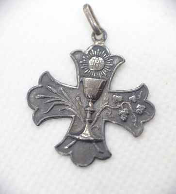 a silver cross with a sun on top of it