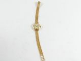 une montre en or avec une chaîne autour du poignet