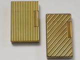 two gold lighters sitting next to each other on a white surface