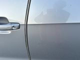 a close up of a car door handle with a dog in the background