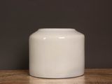 un vase blanc posé sur une table sur fond noir