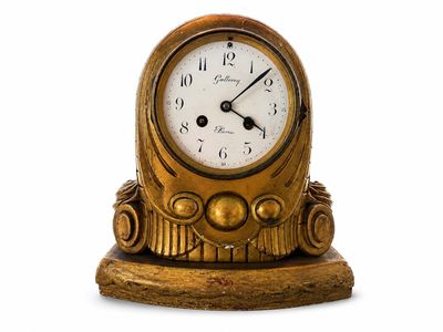 une horloge dorée posée sur un socle, sur fond blanc