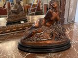 une statue représentant un homme assis sur une table en marbre