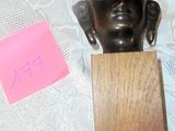 a bronze head of a person on a wooden block