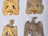 quatre broches en forme d'aigle en or et une clochette dorée sur un fond blanc