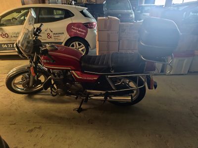 une moto garée dans un garage, avec des cartons à l'arrière