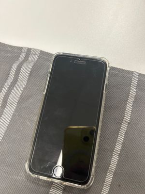Un iPhone est posé sur une couverture, sur un lit.