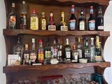 une étagère en bois sur laquelle sont posées de nombreuses bouteilles et verres