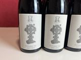 three bottles of red wine are lined up on a table