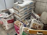 Plusieurs sacs de nourriture sont empilés sur une palette dans une cuisine
