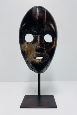 an image of a wooden mask on a stand on a white surface