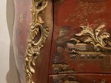 a red and gold chest of drawers with a clock on top