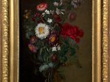 a painting of flowers in a gold frame on the wall