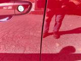 a reflection of a person standing in a red car