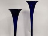 une paire de vases en verre bleu posés sur une table blanche