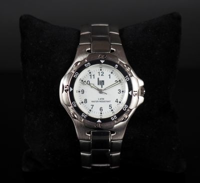a close up of a watch sitting on a pillow on a black surface