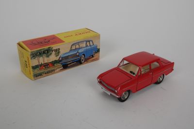 une petite voiture rouge à côté d'une boîte, posée sur une surface blanche