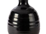 un vase noir posé sur une surface blanche