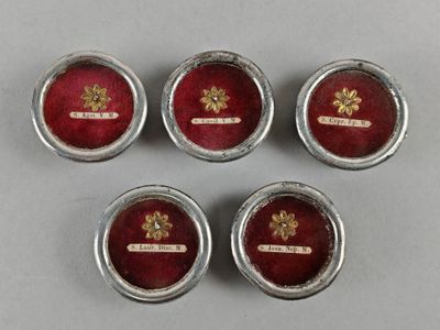 four silver and red buttons with a gold emblem on them
