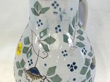 un vase blanc orné de fleurs bleues et vertes et d'un oiseau