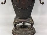 a bronze vase with a bird on it sitting on a stand