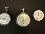 trois montres de poche différentes posées sur une surface noire