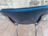 a black chair with a blue seat sitting on a brick floor