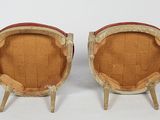 two wooden chairs with red cushions on them sitting on a white surface