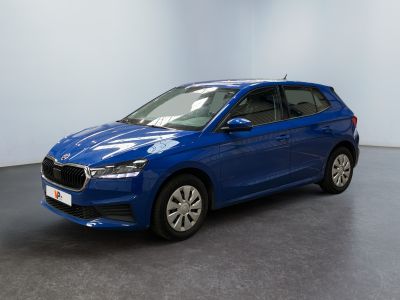 Une voiture bleue est garée dans une pièce aux murs blancs.