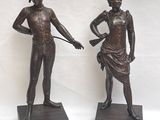 pair of bronze statues of a man and a woman holding a gun