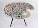 une table sur laquelle se trouve une palette de peinture, sur laquelle est posée une carte