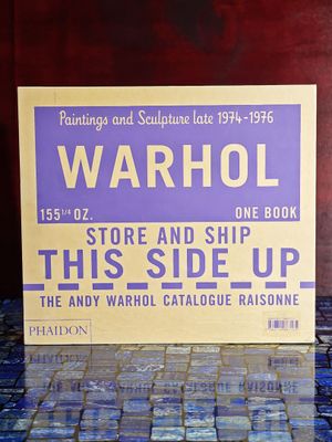 une pancarte sur laquelle on peut lire « Warhol, ce côté vers le haut » posée sur une table