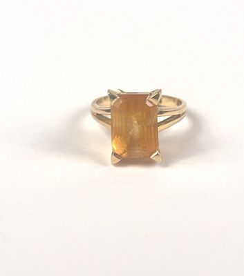 an image of a ring with a yellow stone on a white surface