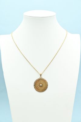 a gold necklace with a medallion pendant on a mannequin