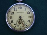 a close up of a pocket watch on a green surface