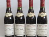 four bottles of wine are lined up on a white surface