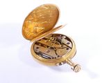 a gold pocket watch that is open on a white surface
