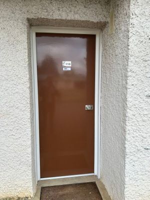 une porte marron dans un coin d'un immeuble blanc