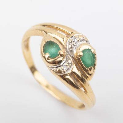 a close up of a gold ring with two emerald stones