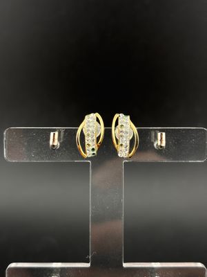 a pair of gold and diamond earrings on a stand