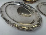 three silver plates on a white table with a gold vase in the background