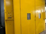 une grande armoire jaune dans un entrepôt, à côté d'une poubelle noire