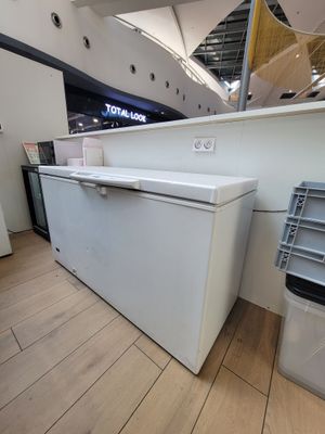 un réfrigérateur blanc posé à côté d'une poubelle dans un magasin