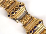 an image of a gold bracelet with blue stones on a white surface