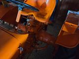 an orange tractor sitting in a room with a wooden wall